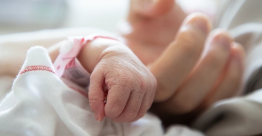 Selective focus photo of an adult touching a newborn's hand.