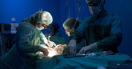 Selective focus photo of a surgical team operating on a patient.